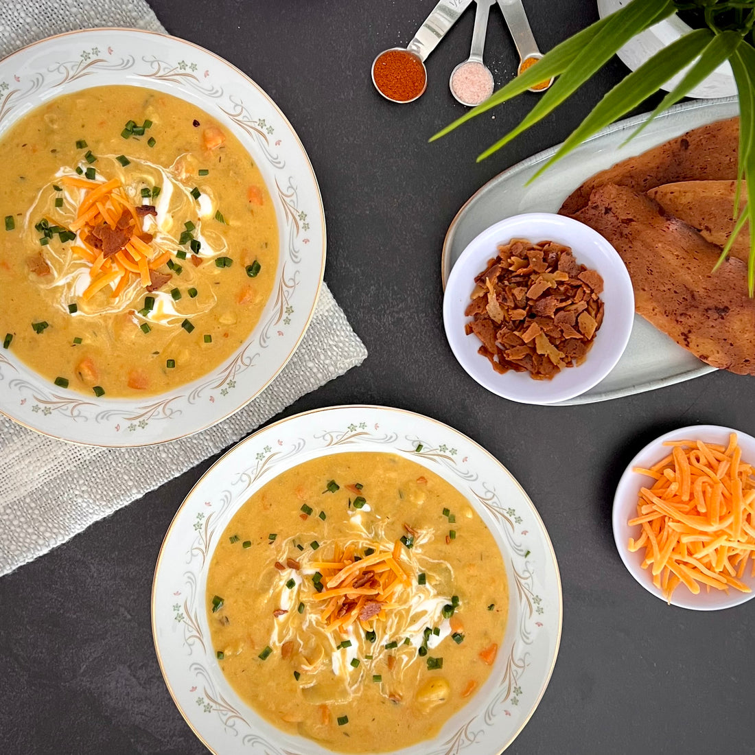 Loaded Potato Soup; A rich, creamy, cheesy soup version of loaded potato is a pure comfort in a bowl. Loaded with tender potatoes, carrots, and chickpeas in a thick creamy broth, topped with plant based smoky bacon pieces and shredded cheese.